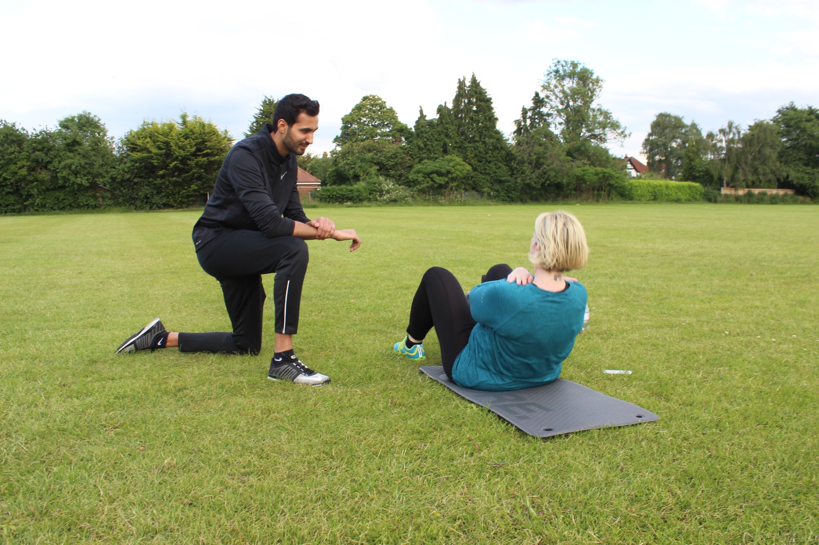 Kam coaching a client through an outdoor training session on the grass